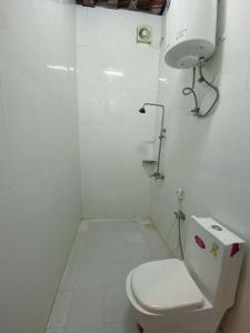 a white bathroom with a toilet and a sink at Bait Aljabal Hospitality Inn in Al Ḩamrāʼ