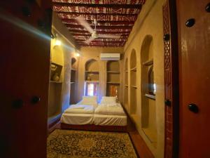 una piccola camera con un letto e un corridoio di Bait Aljabal Hospitality Inn a Al Ḩamrāʼ