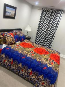 a bed with a blue comforter with red roses on it at TREASURES HOME 5 in Brampton