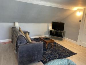 a living room with a couch and a tv at Busby Apartments in Carmunnock