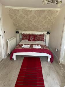 a bedroom with a red bed with a red rug at Busby Apartments in Carmunnock
