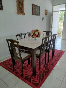 a dining room table and chairs on a red rug at HOMESTAY HAIKALHAIDAR in Rantau Panjang