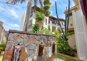 a building with a stone wall and palm trees at Grand Bay Suites in Grand-Baie