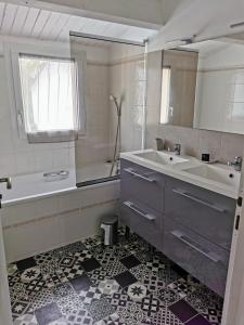 ein Badezimmer mit einem Waschbecken, einer Badewanne und einem Spiegel in der Unterkunft Gîtes, Chambres d'Hôtes La Maison d'Amis in Puilboreau