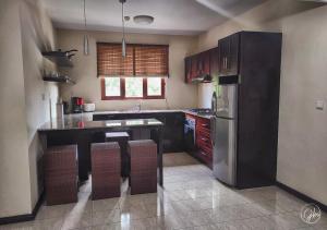 cocina con armarios negros y nevera de acero inoxidable en Grand Bay Suites, en Grand Baie