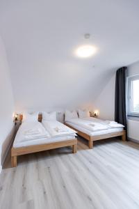 2 Betten in einem Zimmer mit weißen Wänden und Holzböden in der Unterkunft Apartement in Zell in Zell am Main