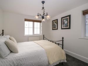 a white bedroom with a bed and a window at Pound Cottage in Lyme Regis