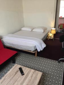 - une petite chambre avec un lit et un fauteuil rouge dans l'établissement Victor Hugo 4 D et sa pizza offerte, à Aurillac