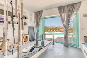 een fitnessruimte met uitzicht op een zwembad en een kamer met een bed bij Pandesia Villas Private Pools in Mármara