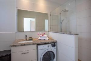 a bathroom with a washing machine and a mirror at Penthouse Apartment next to Blue Bay Golf & Beach! in Willemstad
