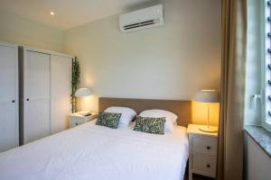 a bedroom with a white bed with two pillows at Penthouse Apartment next to Blue Bay Golf & Beach! in Willemstad