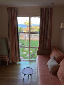 - un salon avec un canapé et une grande fenêtre dans l'établissement Cap Estérel, 2 pièces, jardin, vue mer et piscine, à Agay