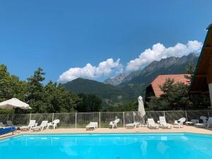 a swimming pool with chairs and a view of mountains at LE NID DU BIRDIE, Giez, Proche du lac d’Annecy in Giez