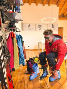 a man sitting on the floor next to a pair of skis at Alp Apartments - Xavier in Aosta