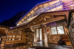 a wooden house with a lit up facade at night at Hôtel Le Samovar in Val-d'Isère