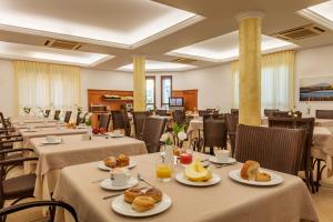 サン・ヴィート・ロ・カーポにあるHotel Sabbia d'Oroのテーブルと椅子、食べ物が備わる広い客室です。