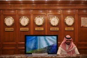 a man sitting in front of a tv in a room with clocks at Casablanca Hotel Jeddah in Jeddah