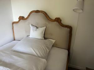 uma cama com cabeceira com almofadas brancas em Kruemelkate em Witzwort