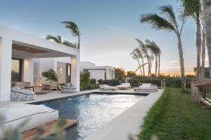 a villa with a swimming pool and palm trees at TAF Beach Villas with Tesla in Tigaki