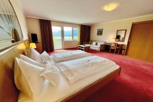 a hotel room with a bed with white sheets at Hotel Pachernighof in Velden am Wörthersee