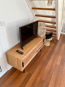a flat screen tv sitting on top of a wooden entertainment center at Maison bohème à deux pas de l'océan in Lège-Cap-Ferret