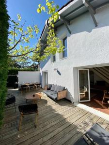 a patio with a couch and a table on a deck at Maison bohème à deux pas de l'océan in Lège-Cap-Ferret