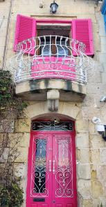 a pink door and a balcony on a building at 1500 Little Pink House in Kalkara Creek in Kalkara