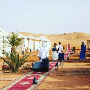 un grupo de personas caminando por un camino en el desierto en Sahara Luxury Tented Camp, en Merzouga