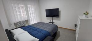 a bedroom with a blue bed and a flat screen tv at Appartamento Laura in Merano
