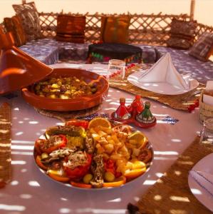 una mesa con un plato de comida en una mesa en Sahara Luxury Tented Camp en Merzouga