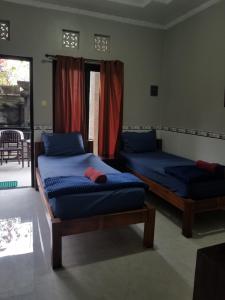 a bedroom with two beds and a window with a patio at Jepun Segara Guest House in Kuta