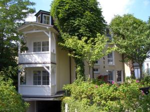 a large white building with trees and bushes at Villa Ambienta WE 7 in Binz