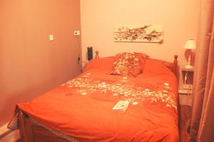 Un dormitorio con una cama con sábanas naranjas y flores. en Pause sérénité dans le centre-ville ville de Périgueux, en Périgueux