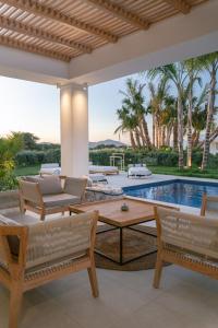 un patio con mesa, sillas y piscina en TAF Beach Villas with Tesla, en Tigaki