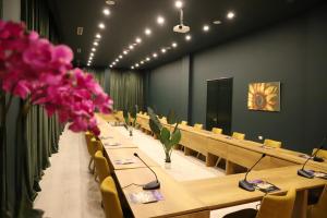 una sala de conferencias con mesas, sillas y flores rosas en Hotel Colombo, en Berat