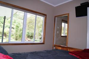 a bedroom with a bed and a mirror at Gully Retreat Karapiro in Cambridge