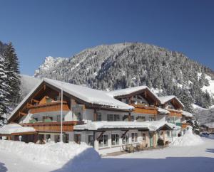 a ski lodge in the snow with a mountain at Landhotel Berghof in Bad Hindelang