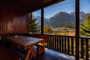 a room with a wooden table on a balcony with mountains at The Bear House 2 in Buşteni