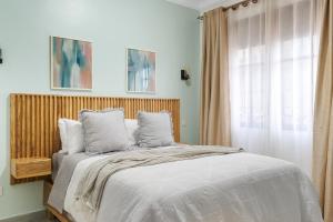 a bedroom with a bed with a wooden headboard and a window at Polo Apartments in Kampala