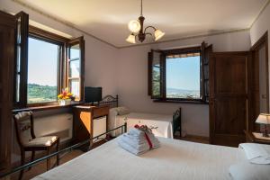 a room with a bed and a desk and windows at Agriturismo La Rocca Assisi in Petrignano