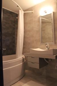 een badkamer met een wastafel, een bad en een douche bij Stenata Boutique Apartments in Pamporovo