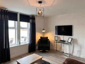 a living room with a chair and a flat screen tv at Crown street getaway in Ayr