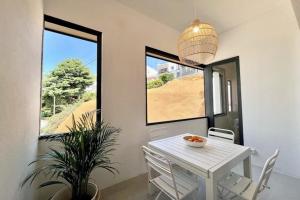 a dining room with a white table and chairs and windows at Hauzify I Apartaments Sant Pau in San Pol de Mar