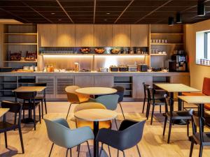 フロート・ベイハールデンにあるibis Brussels Groot Bijgaardenのテーブルと椅子のあるレストラン、キッチンが備わります。
