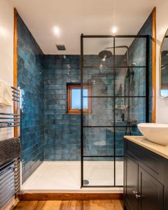 a bathroom with a shower with blue tiles at Coorie View in Kilmore