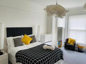 a bedroom with a bed with yellow pillows and a chair at Golden Triangle Ensuites in Norwich