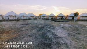 un groupe de tentes blanches dans un champ dans l'établissement Rann Visamo Resort, à Bherandiāla