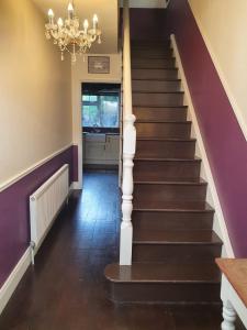 a staircase with purple walls and a chandelier at The Retreat in Carlingford