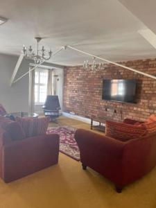 a living room with two couches and a brick wall at Chandeliers 6 in Shrewsbury