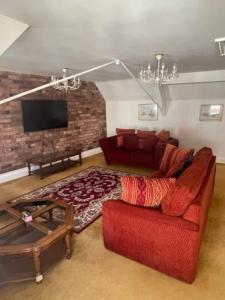 ein Wohnzimmer mit einem roten Sofa und einem TV in der Unterkunft Chandeliers 6 in Shrewsbury